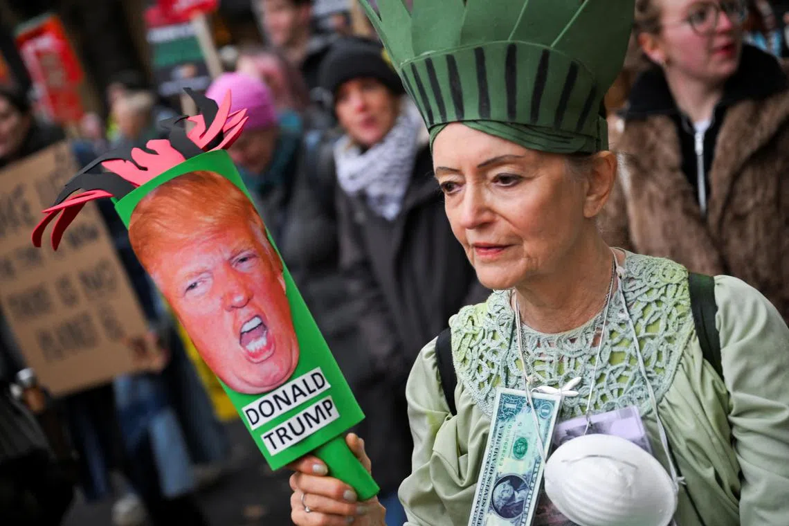 A woman shows an illustration of US President-elect Donald Trump, during a protest against the UN COP29  in Baku, in London.