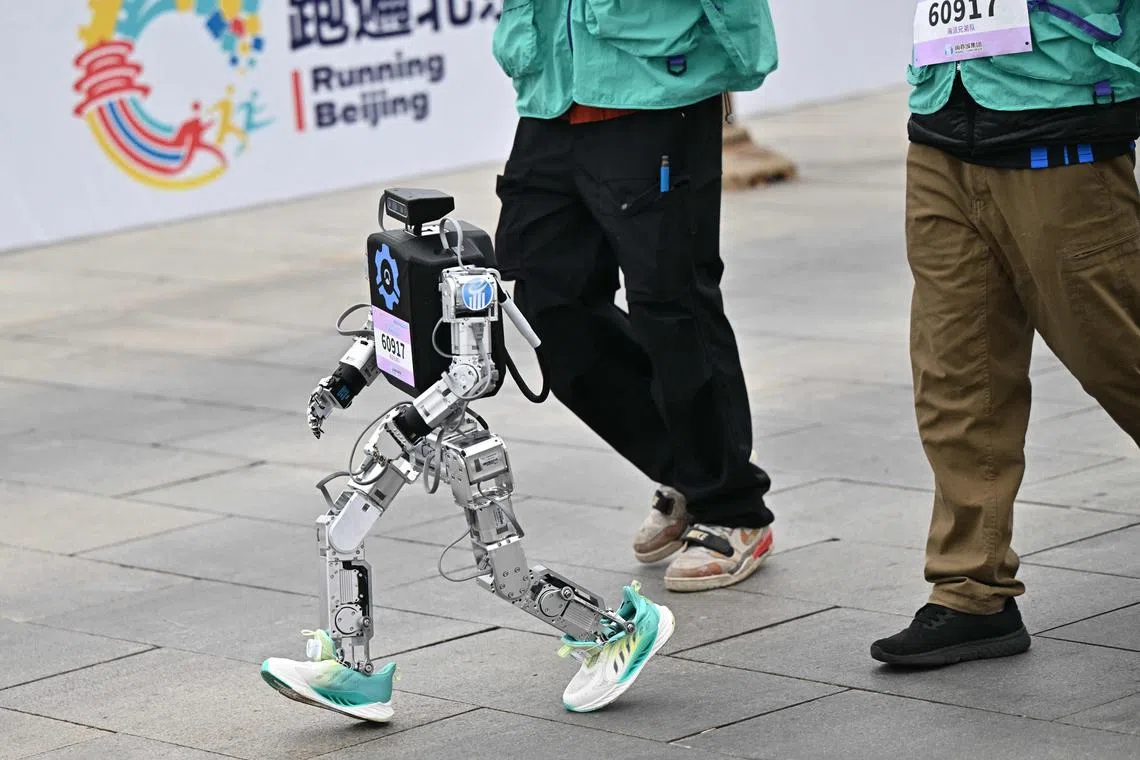 A robot takes part in the humanoid robot half marathon in Beijing on April 19, 2025. Dozens of humanoid robots took to the streets of Beijing, joining thousands of their flesh-and-blood counterparts in a world-first half marathon showcasing China's drive to lead the global race in cutting-edge technology. (Photo by Pedro Pardo / AFP)