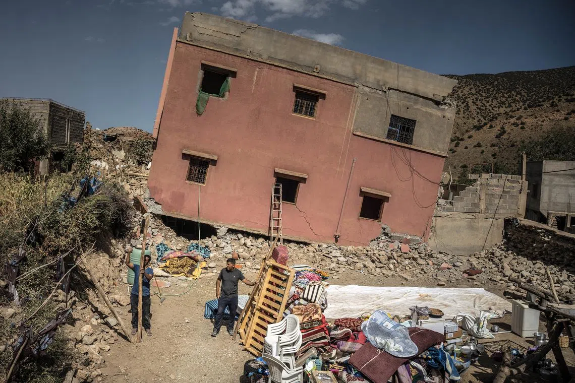 Men standing in front of their house as they erect a temporary shelter in Douar Tnirt village in the Atlas Mountains, in the hard-hit Al Haouz province, Morocco, on Sept 10, 2023. 