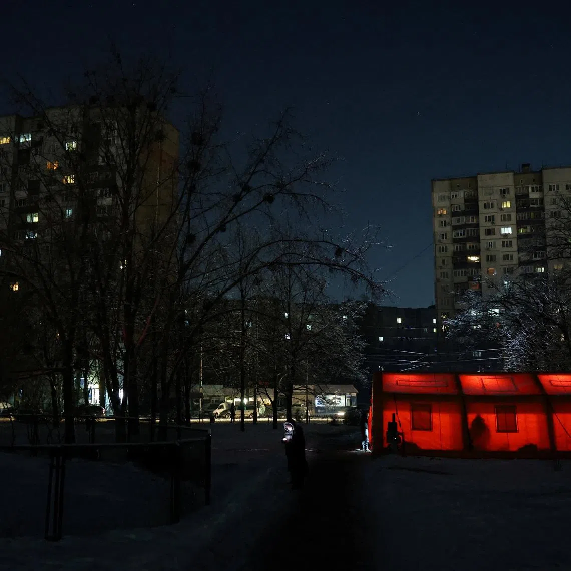 A resident stands near tents of a government-run humanitarian aid points, where residents can warm up, charge their devices, get hot drinks and psychological support, installed next to apartment buildings, during a power blackout after critical civil infrastructure was hit by overnight Russian missile and drone strikes, amid Russia's attack on Ukraine, in Kyiv, Ukraine, January 20, 2026. REUTERS/Anatolii Stepanov