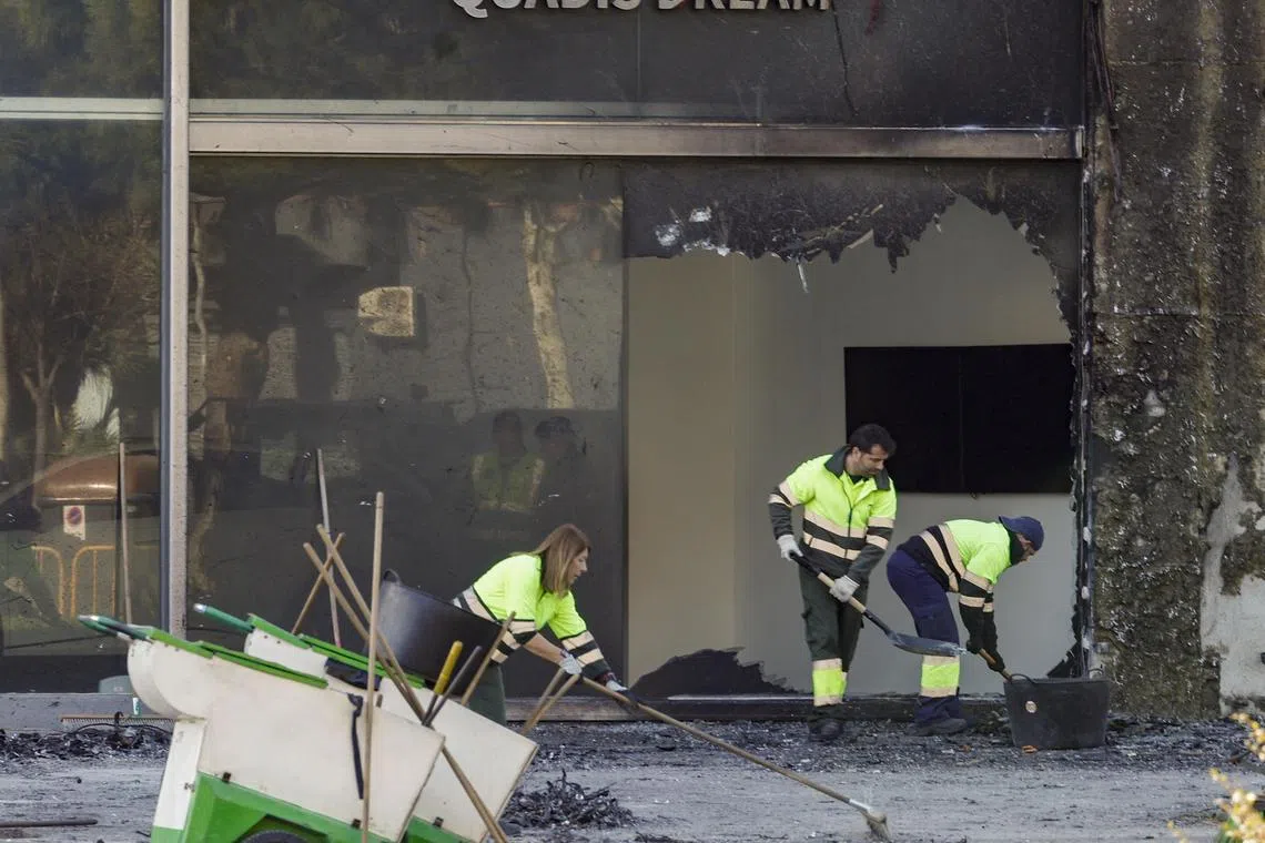 Municipal workers clean the area around the two buildings that were destroyed in a fire in Valencia. Ten days later, another fire in Villajoyosa killed three from the same family.