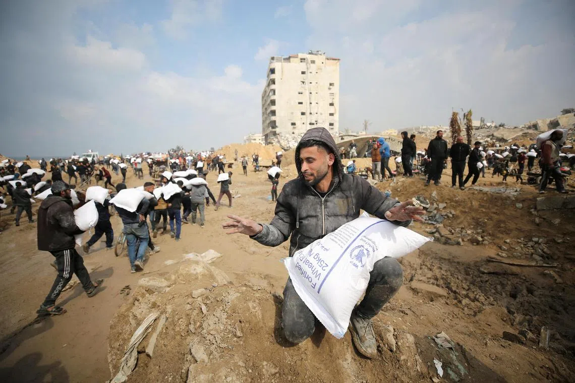Palestinians carry bags of flour they grabbed from an aid truck near an Israeli checkpoint.