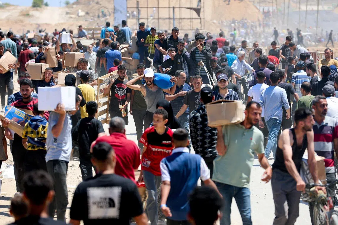 FILE PHOTO: Palestinians carry aid supplies which they received from the U.S.-backed Gaza Humanitarian Foundation, in the central Gaza Strip, May 29, 2025. REUTERS/Ramadan Abed/File Photo
