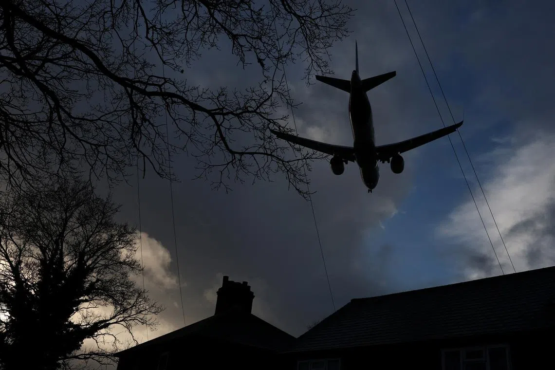 FILE PHOTO: A passenger plane flies over houses as it makes its landing approach to Heathrow Airport in west London, Britain, January 28, 2025.  REUTERS/Toby Melville/File Photo