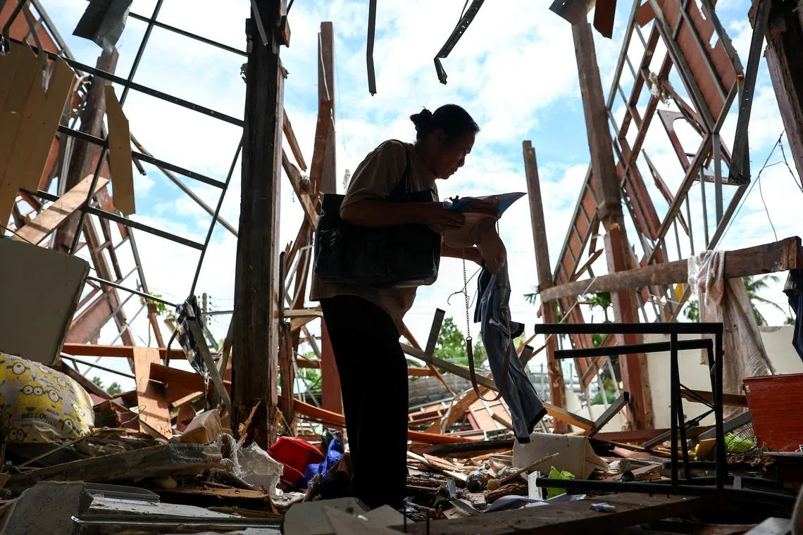 A woman collecting items from her house destroyed during Cambodia's artillery attacks, in Sisaket province, Thailand, on July 29, 2025. 