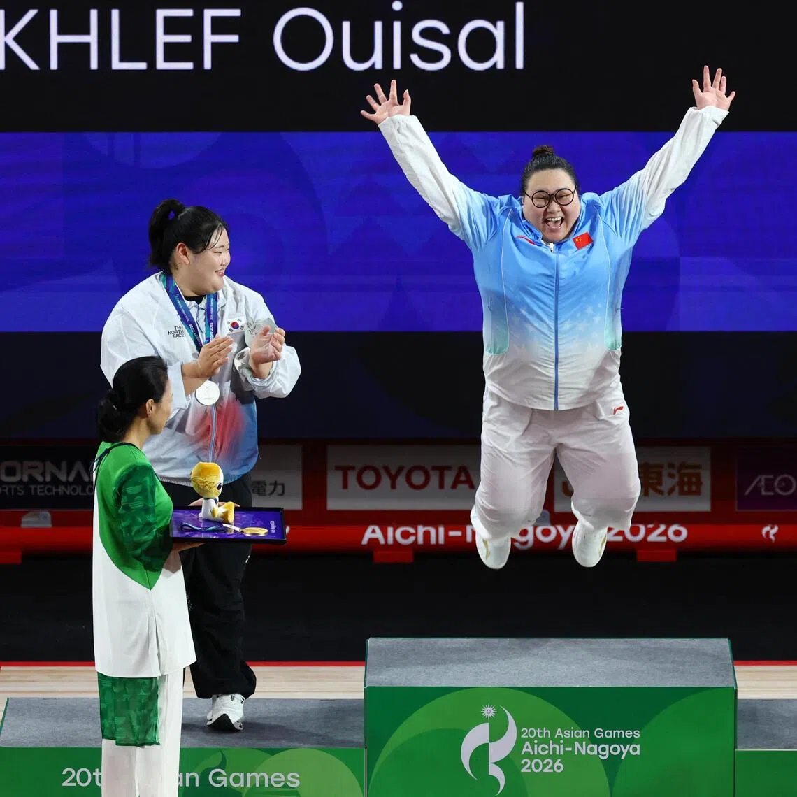Gold medallist Li Wenwen of China jumping for joy on the podium after winning the women’s +86kg, as silver medallist South Korea’s Park Hye-jeong  and bronze medallist Qatar’s Ouisal Ikhlef look on.