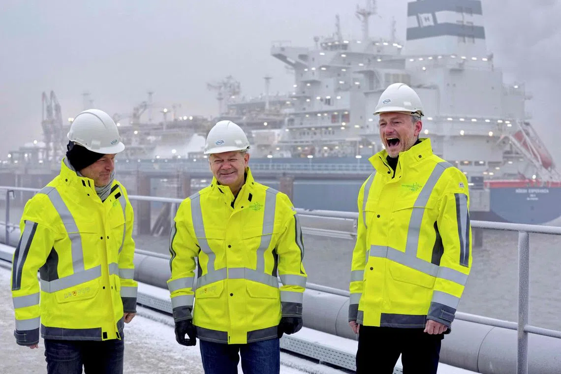 (From left) German Minister of Economics and Climate Protection Robert Habeck, German Chancellor Olaf Scholz, and German Finance Minister Christian Lindner pose in front of the Floating Storage and Regasification Unit ship.