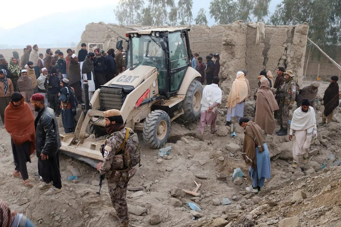 FILE PHOTO: Residents gather near a damaged house as a loader clears debris, following the Pakistani airstrikes, in Bihsud district, Nangarhar province, Afghanistan, February 22, 2026. REUTERS/Stringer/File Photo