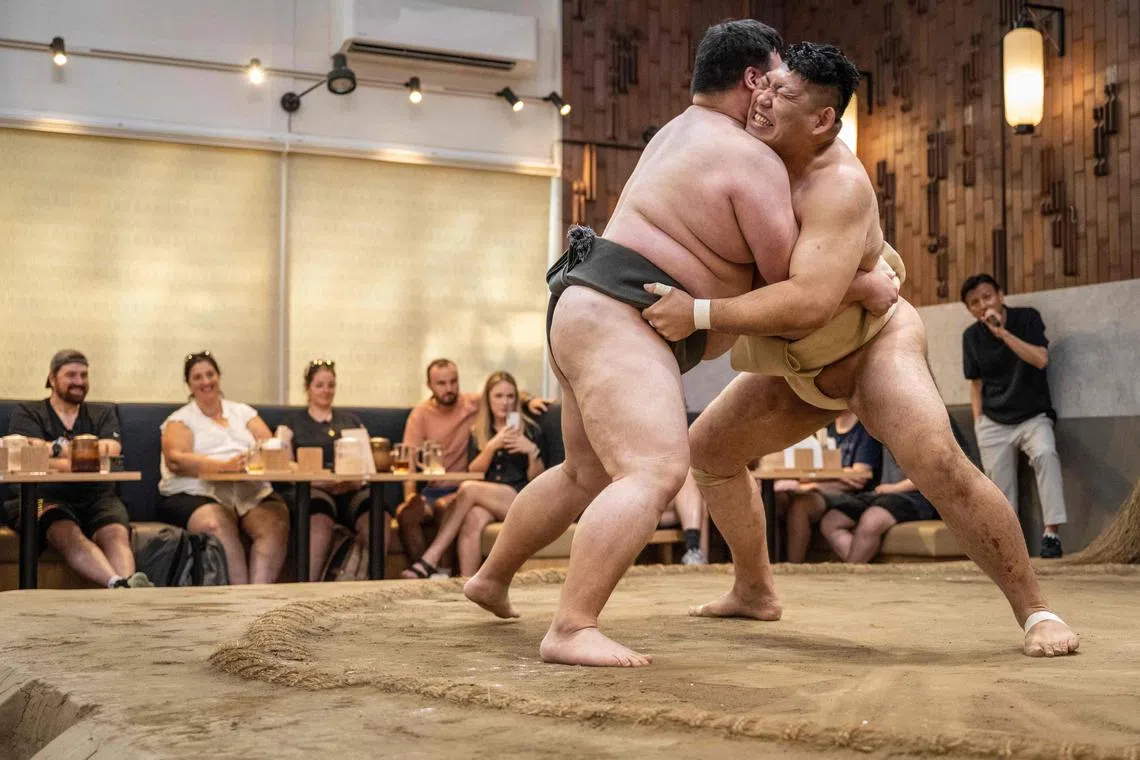 Former sumo wrestlers taking part in a demonstration match in front of tourist at the Yokozuna Tonkatsu Dosukoi Tanaka restaurant in Tokyo.