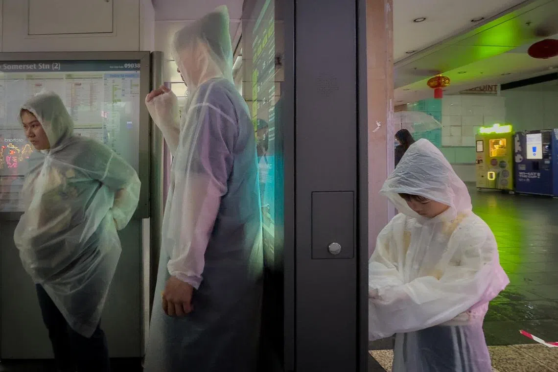 Commuters in raincoats waiting for a bus at a bus stop along Orchard Road on Jan 10, 2025