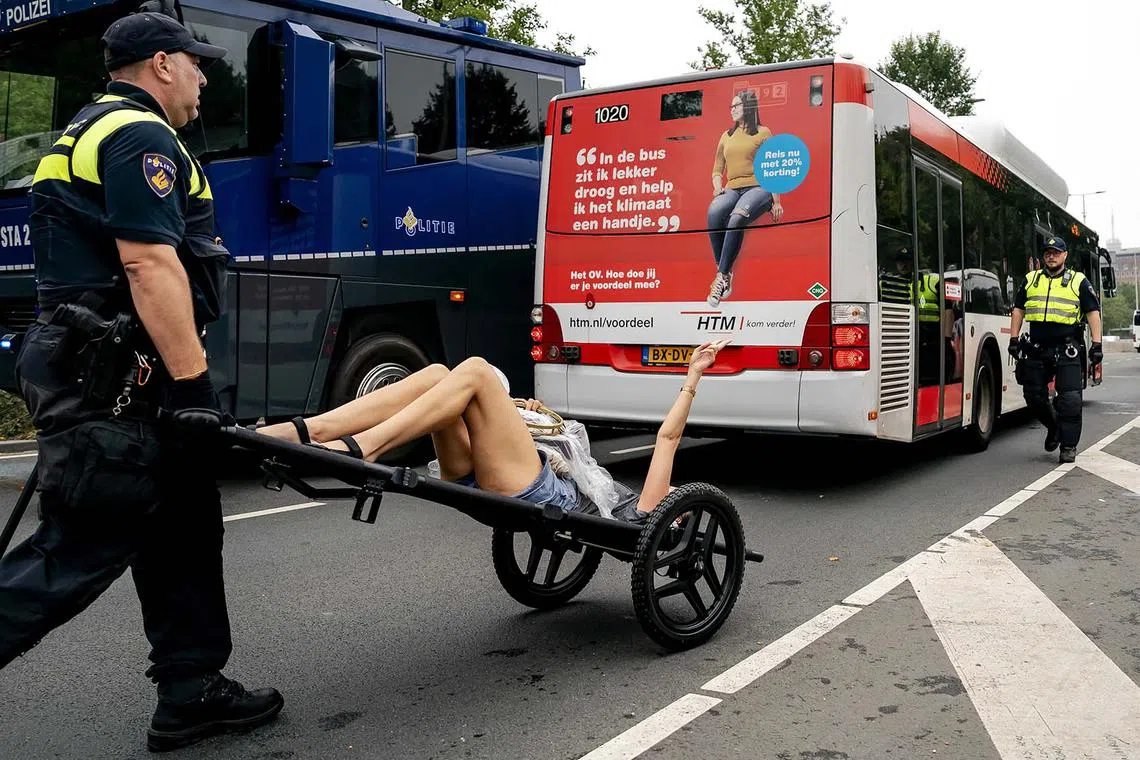Police intervene as climate activists block the A12 motorway for the third day in a row to demonstrate against the government's granting of fossil subsidies, in The Hague, Netherlands, Sept 11.