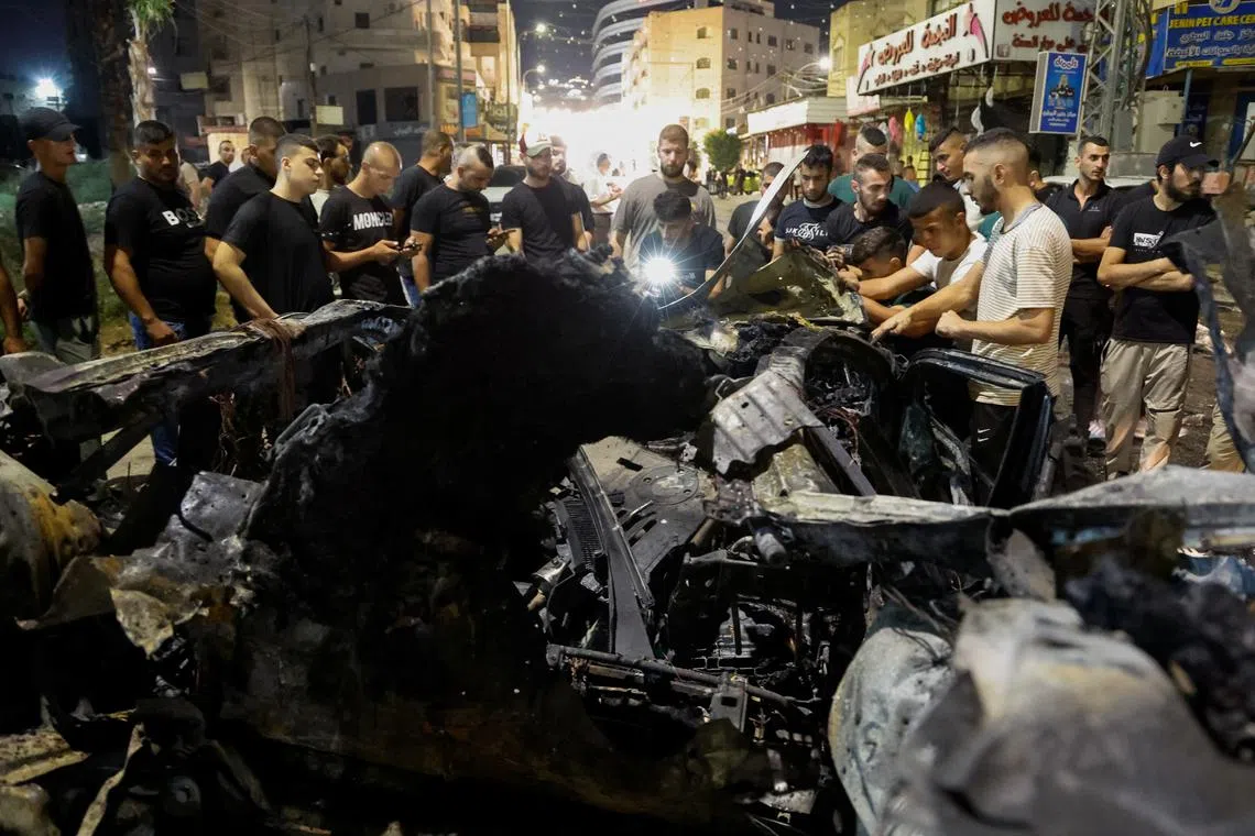 Palestinians inspect a car damaged in an Israeli airstrike, in Jenin, in the Israeli-occupied West Bank, August 17, 2024. REUTERS/Raneen Sawafta
