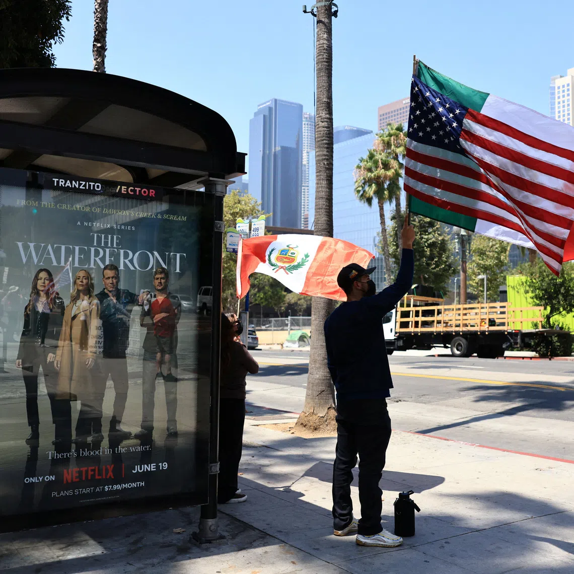 A man holds flags during a protest against federal migration enforcement in downtown Los Angeles, California, U.S. August 2, 2025. REUTERS/David Swanson