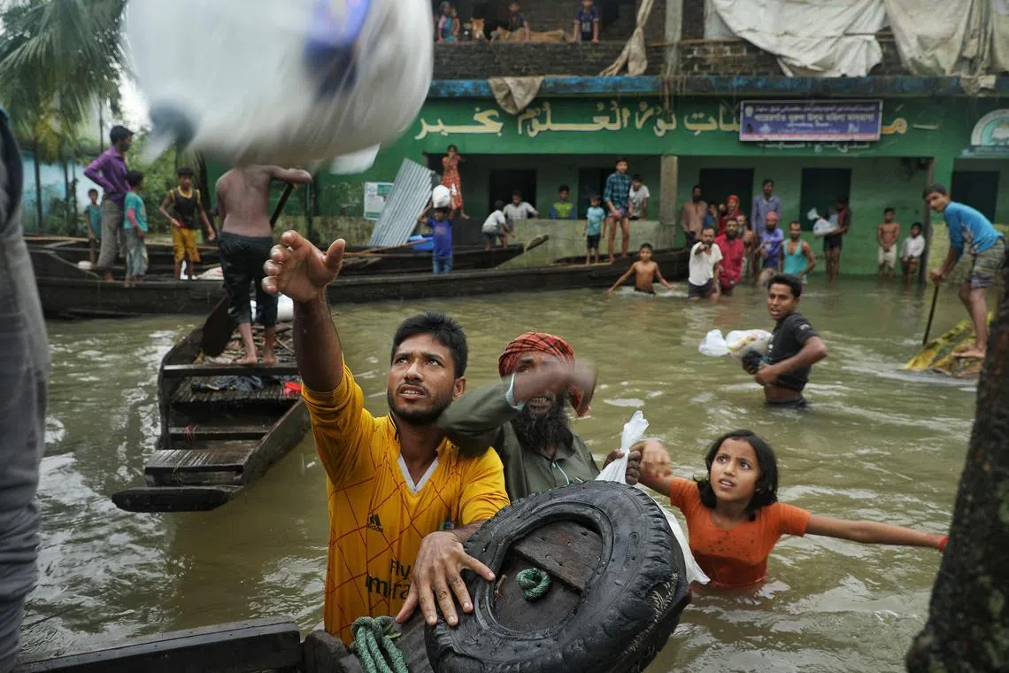 People collect food aid following heavy monsoon rainfalls in Companiganj in Bangladesh on June 20, 2022. - . (Photo by Maruf RAHMAN / AFP)