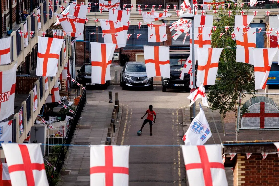 A child with a football in Kirby Estate, where residents have put up over 400 St George's flags, ahead of England's first FIFA World Cup 2026 match, in south London, Britain, on June 16, 2026. 