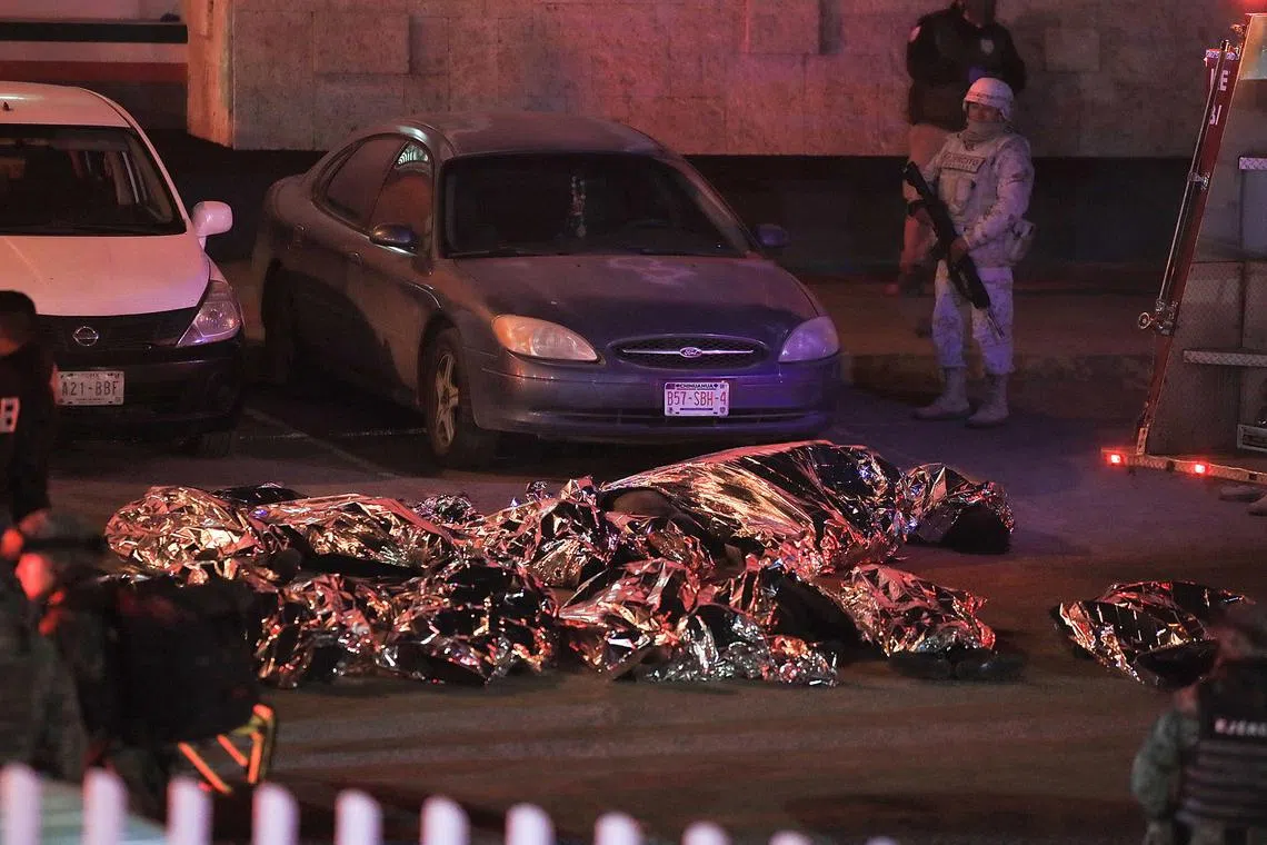 The bodies of some of the 39 migrants who died during a fire at a migrants' facility in Mexico are lined up on a pavement.