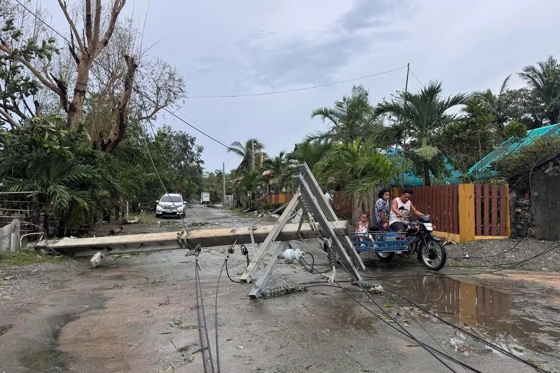 epa12399300 Villagers ride on a three-wheeled motorcycle next to a toppled electric post in the typhoon-hit town of Pagudpud, Ilocos Norte province, Philippines, 23 September 2025. The Philippine weather service said Super Typhoon Ragasa passed over Luzon Island, causing flooding, landslides, and damage to homes and infrastructure.  EPA/BERNIE SIPIN DELA CRUZ