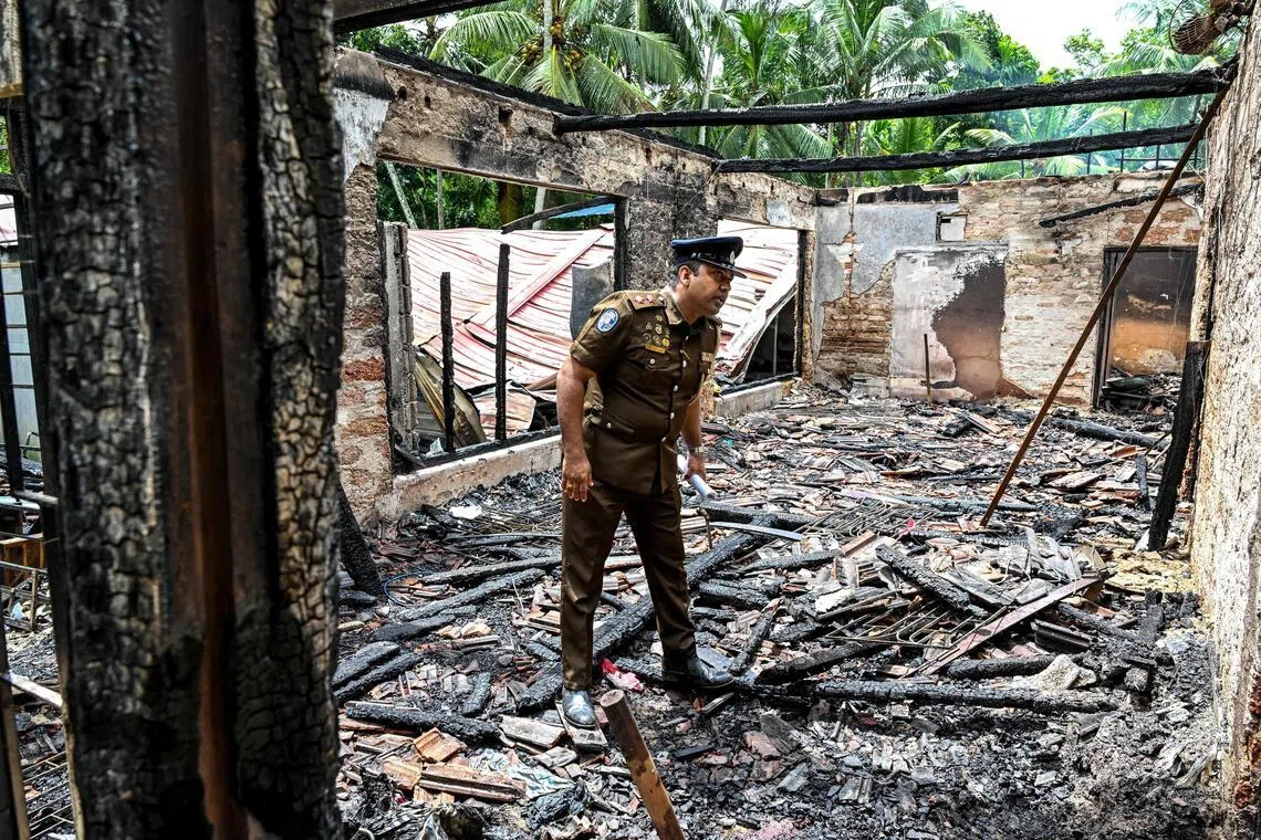 A policeman inspects a burnt elder care home in Sri Lanka's Batagoda, a day after a fire broke outand killed 12 residents.