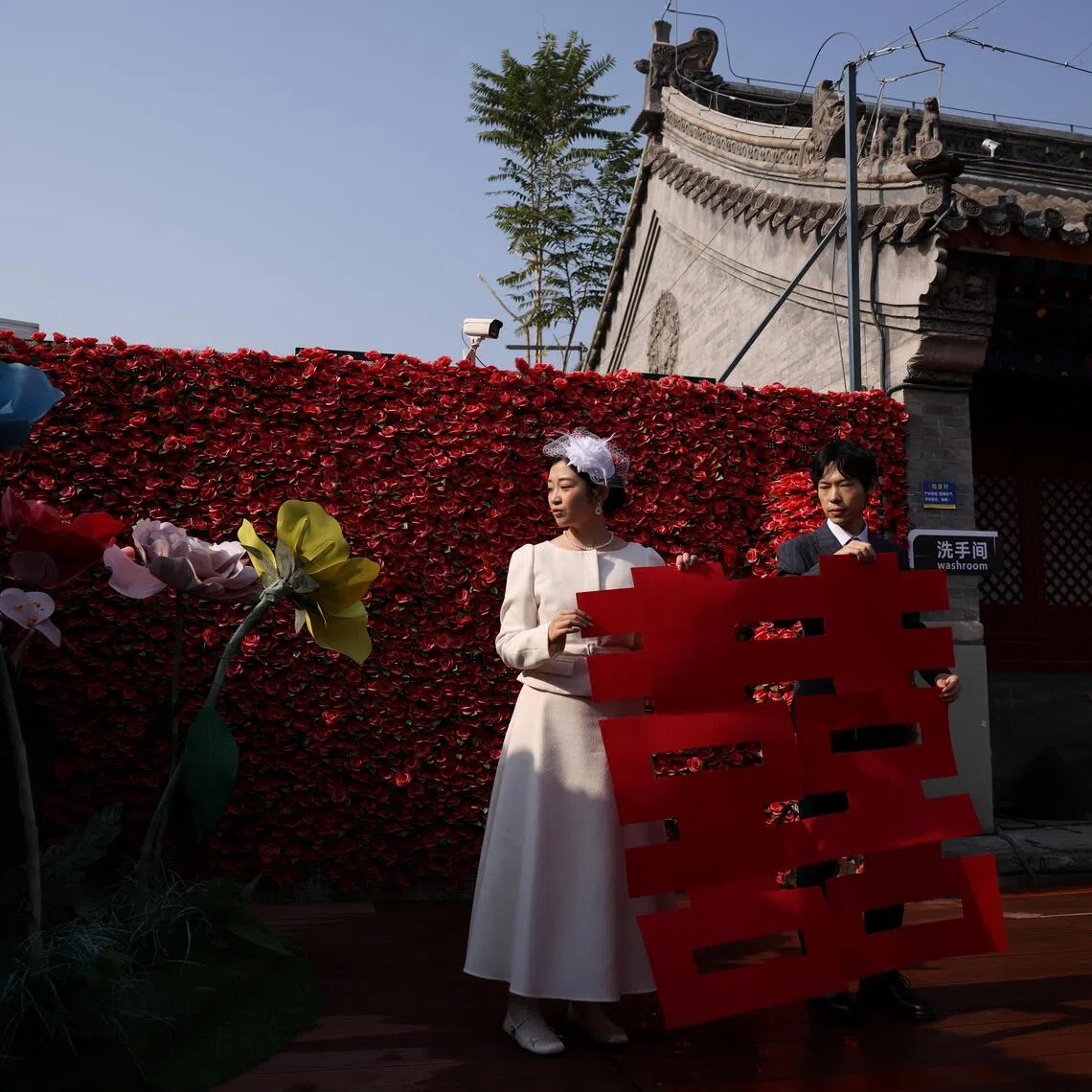 A newlywed couple holding a giant cut-out of the Chinese character Xi, which reads double happiness,   after they registered their marriage at the Huguo Guanyin Temple, in Beijing, China.