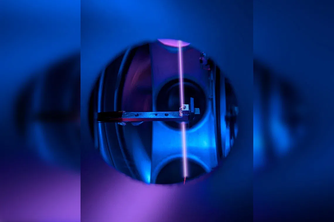 A calcium fluoride crystal is seen in its holder, inside the vacuum system of a nuclear clock at TU Wien, in Vienna, Austria. A laser beam probes thorium nuclei trapped in the crystal.