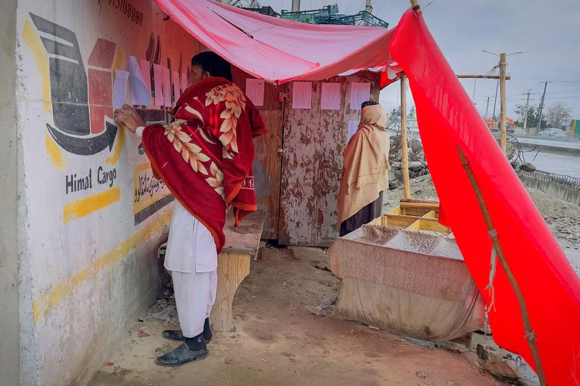 Afghan men search for the names of missing relatives on a list at the site of a drug rehabilitation center destroyed in what the Taliban said was a Pakistani airstrike in Kabul, Afghanistan, March 18, 2026.
