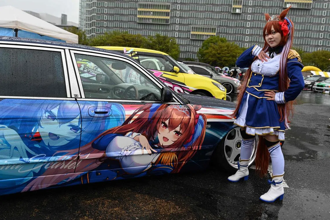 A woman dressed up as anime character Daiwa Scarlet posing next to a car owned by Mr Yosuke Takahata with the same design.