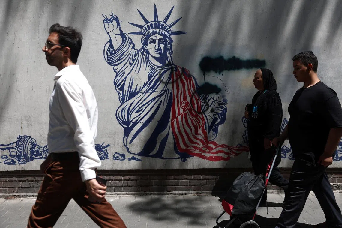 People walk past an anti-US mural on a street in Tehran on June 1.