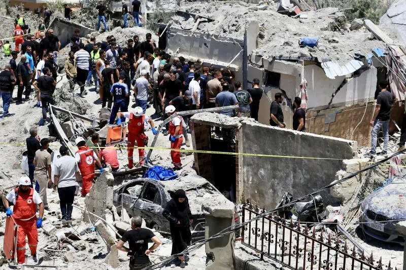 Lebanese rescuers and civilians gathering at the site of an Israeli airstrike on the town of Qannarit, Sidon district, southern Lebanon, on June 20.