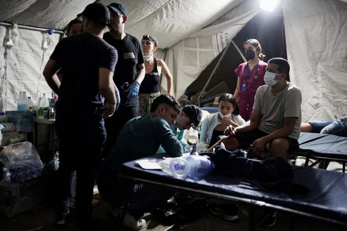 Medical staff attending to a rescuer at the site of a collapsed building following an earthquake in Cali, Colombia, on Aug 10.