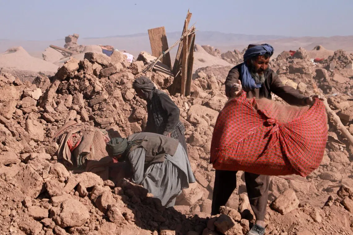 Afghan residents clearing debris of damaged houses after earthquake in Nayeb Rafi village, Zendeh Jan district of Herat province on Oct 10. 