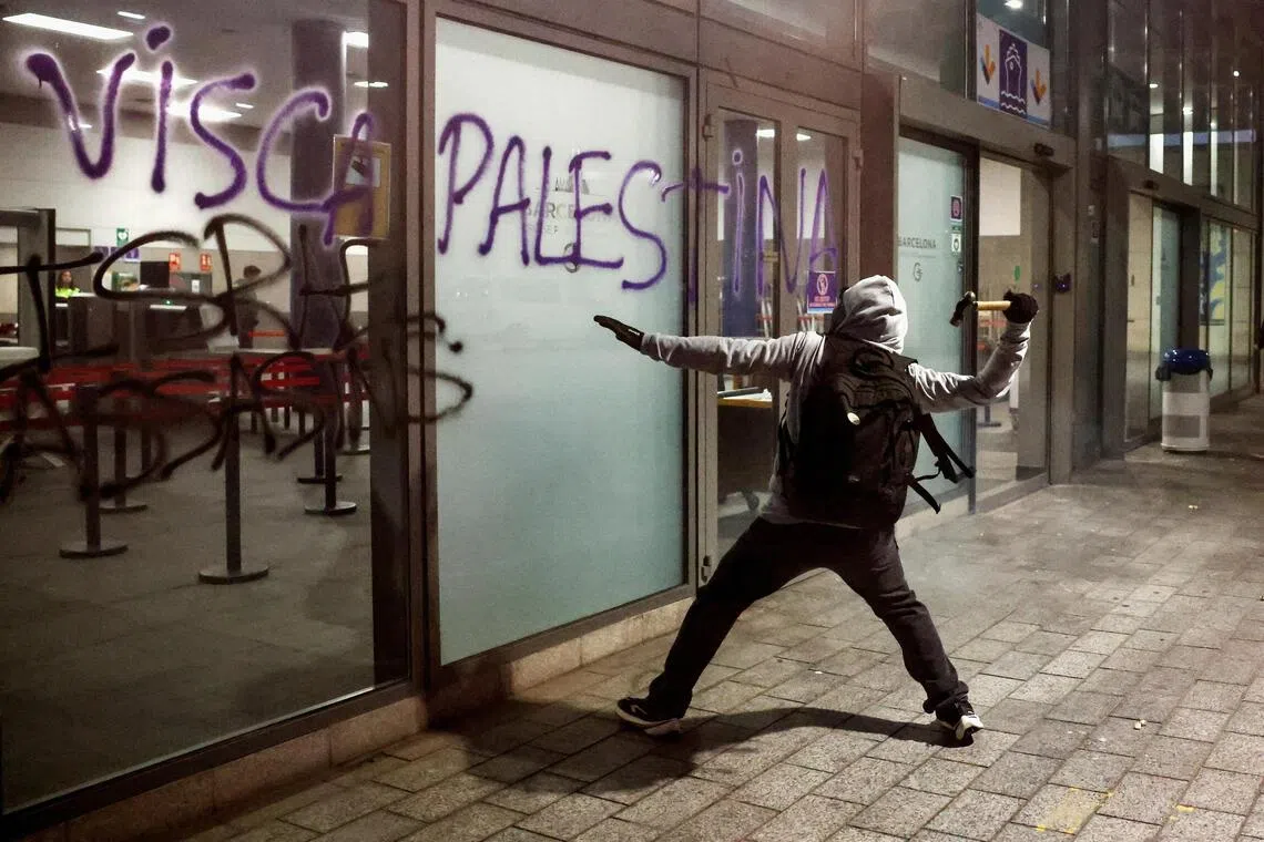 A protester preparing to hit a glass panel at a ship terminal in Barcelona, Spain, with a hammer, on Oct 2.