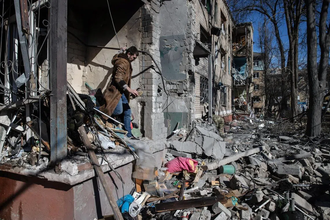 A resident salvages a pair of shoes from the wreckage of an apartment building following a Russian attack, in Kramatorsk, in eastern Ukraine, on March 14, 2023. 