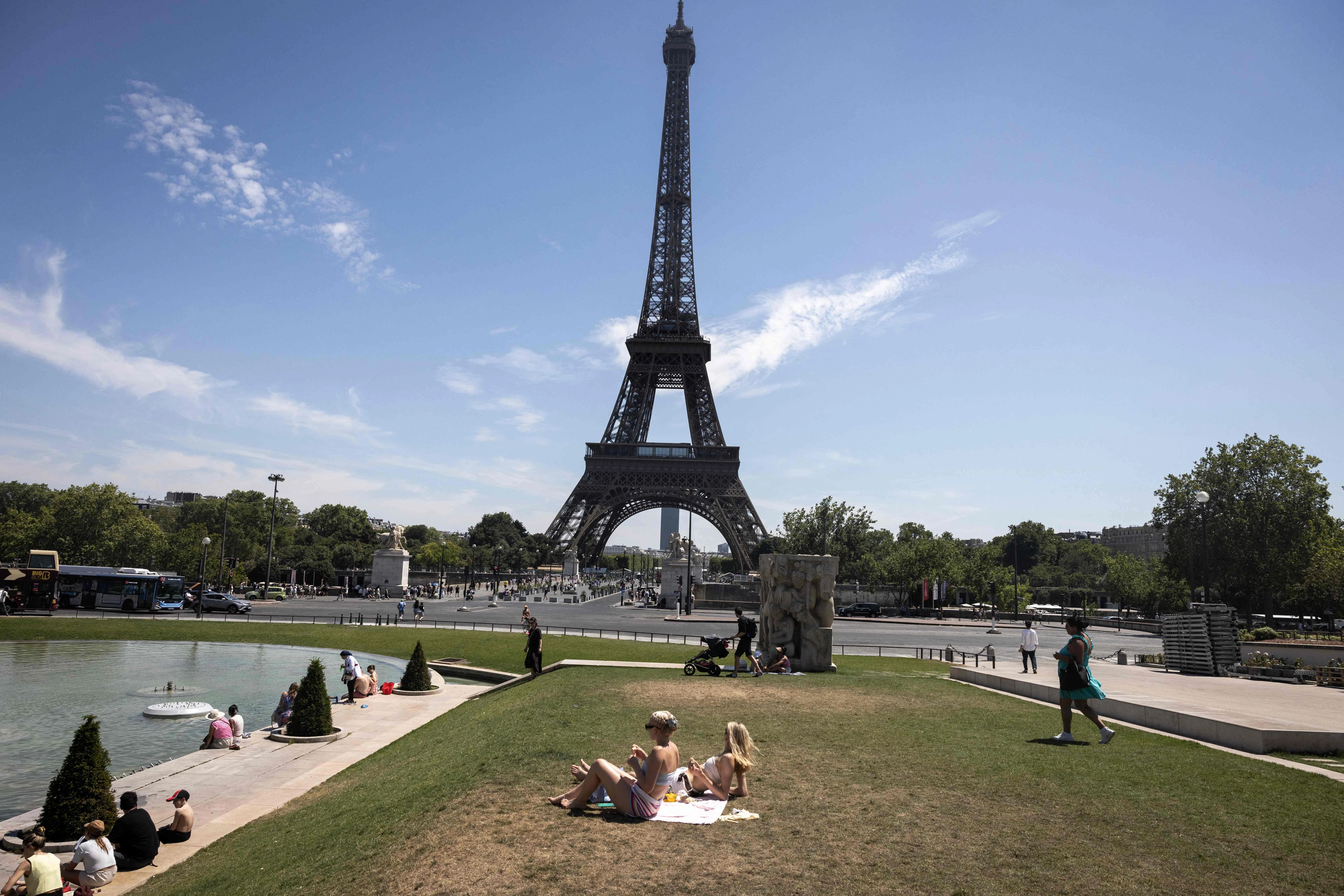 Women sunbathe at the Jardin du Trocadero, near the Eiffel Tower in Paris on July 10, 2026, as a new heatwave hits France. (Photo by Behrouz MEHRI / AFP)