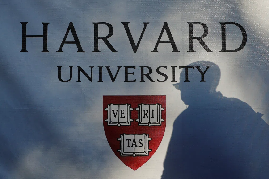 A pedestrian casts a shadow on a Harvard University sign after U.S. President Donald Trump said that his administration was close to a deal with Harvard University, in Cambridge, Massachusetts, U.S., September 30, 2025.   REUTERS/Brian Snyder