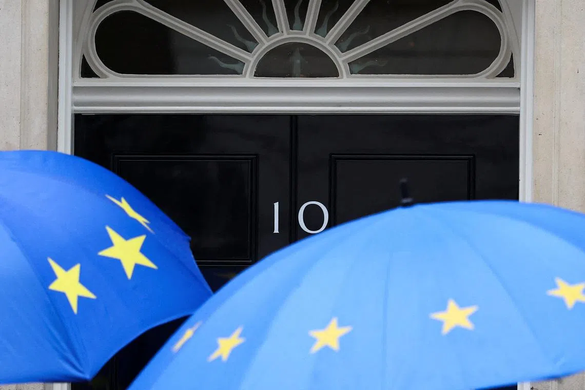People shielding themselves from the rain with EU-themed umbrellas arrive at 10 Downing Street, in London, Britain, June 2, 2026. REUTERS/Toby Melville