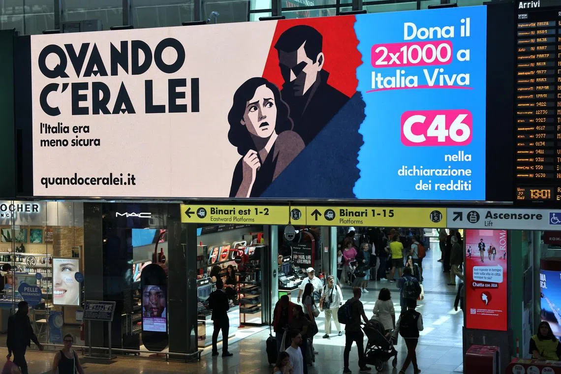 People walk past an advertisement, commissioned by Italia Viva at Roma Termini railway station, referring to Italian Prime Minister Giorgia Meloni, reading in English, and featuring imagery and typography reminiscent of Italian fascist-era propaganda from the 1930s, in Rome, Italy, May 22, 2026. 
