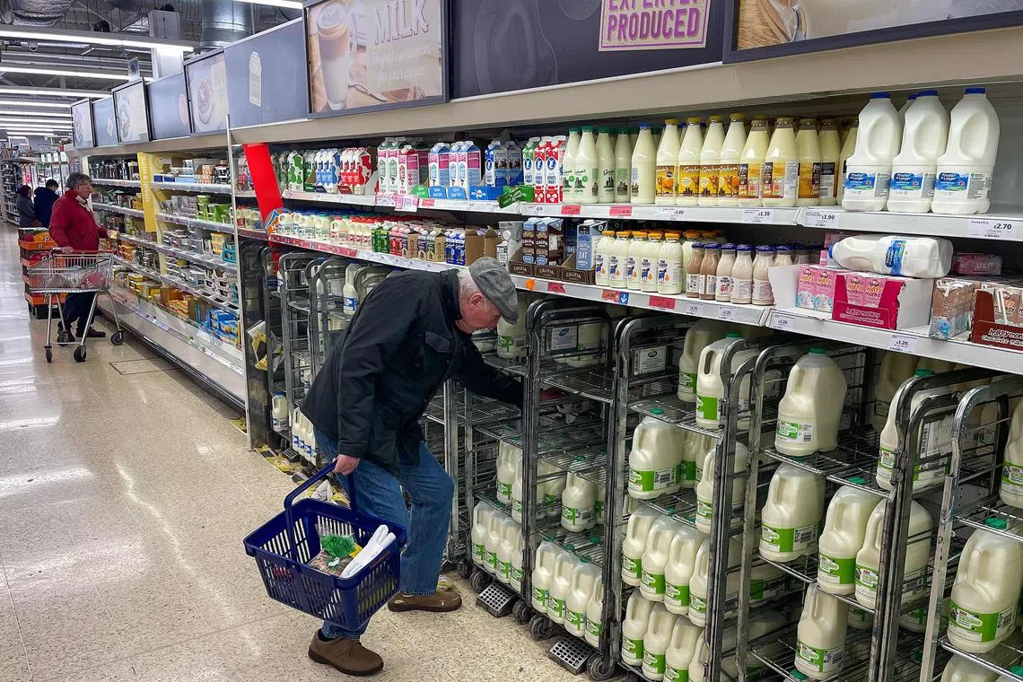 A customer shops for milk inside a Sainsbury's supermarket in east London on February 20, 2023. - British retail sales rebounded surprisingly in January on falling fuel costs and discounting by online and physical stores, official data showed Friday. At the same time, food sales dropped 0.5 percent, the ONS said, following large price rises over the past year. (Photo by Daniel LEAL / AFP)