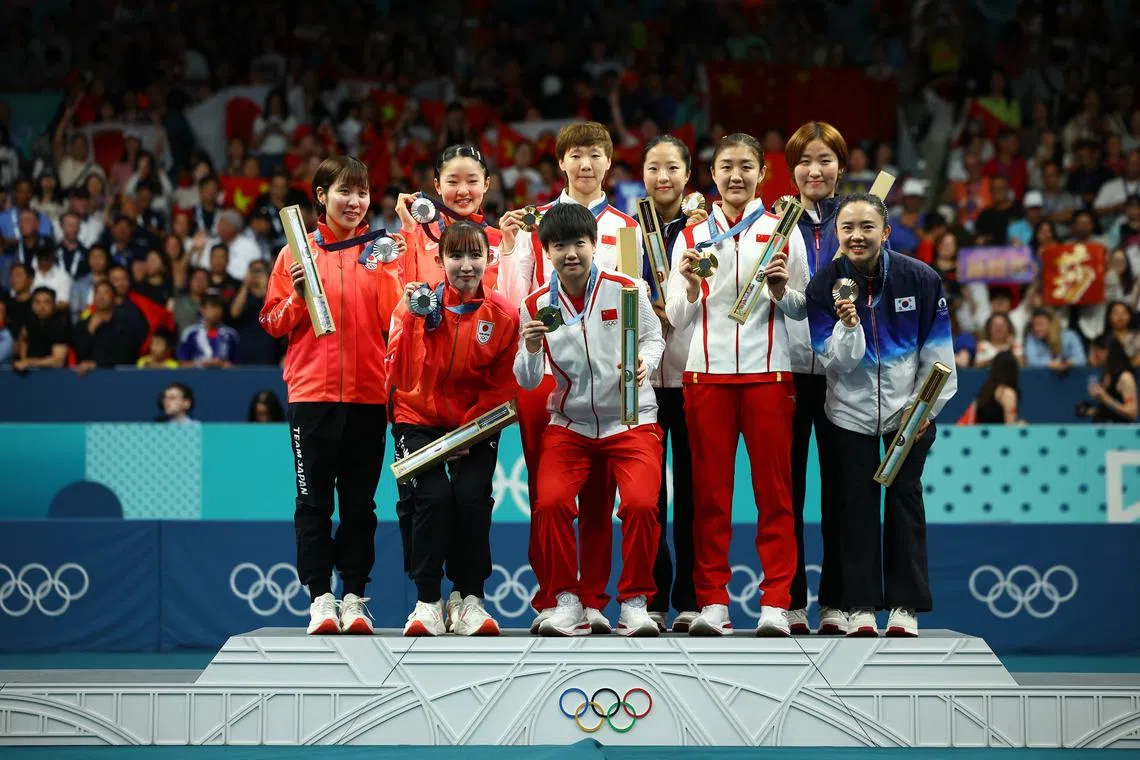 Paris 2024 Olympics - Table Tennis - Women's Team Victory Ceremony - South Paris Arena 4, Paris, France - August 10, 2024. Gold medallists Manyu Wang of China, Yingsha Sun of China, and Meng Chen of China celebrate with their medals on the podium after winning, with silver medallists Miu Hirano of Japan, Hina Hayata of Japan, and Miwa Harimoto of Japan, and bronze medallists Yubin Shin of South Korea, Eunhye Lee of South Korea, and Jihee Jeon of South Korea. REUTERS/Kim Hong-Ji