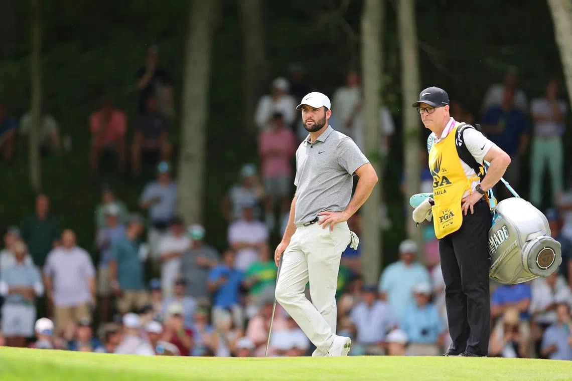 Scottie Scheffler and caddie Brad Payne prepare to putt on the sixth green during the third round of the PGA Championship.