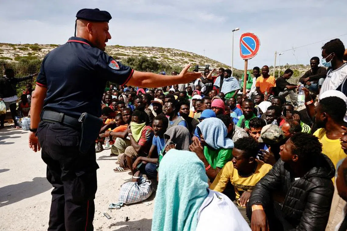 FILE PHOTO: A member of the Carabinieri gestures towards migrants outside the hotspot, on the Sicilian island of Lampedusa, Italy, September 16, 2023. REUTERS/Yara Nardi/File Photo