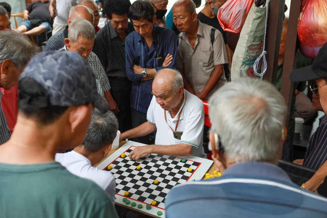 Men watching a chess match in Chinatown, 20 February 2023. Can be used for stories about elderly, seniors, active ageing, ageing population.