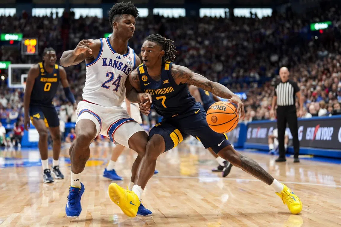 Dec 31, 2024; Lawrence, Kansas, USA; West Virginia Mountaineers guard Javon Small (7) drives against Kansas Jayhawks forward KJ Adams Jr. (24) during the first half at Allen Fieldhouse. Mandatory Credit: Jay Biggerstaff-Imagn Images