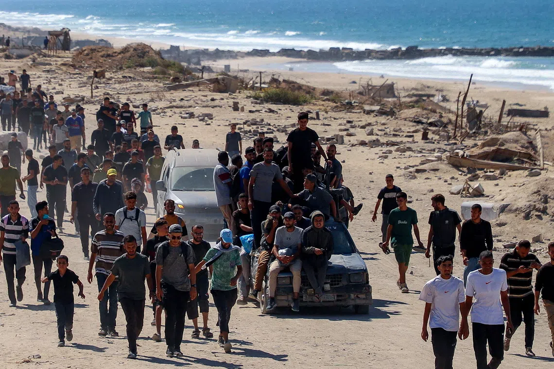 Palestinians, who were displaced to the southern part of Gaza at Israel's order during the war, make their way following their arrival in Gaza City after a ceasefire between Israel and Hamas in Gaza went into effect, October 10, 2025. REUTERS/Ebrahim Hajjaj