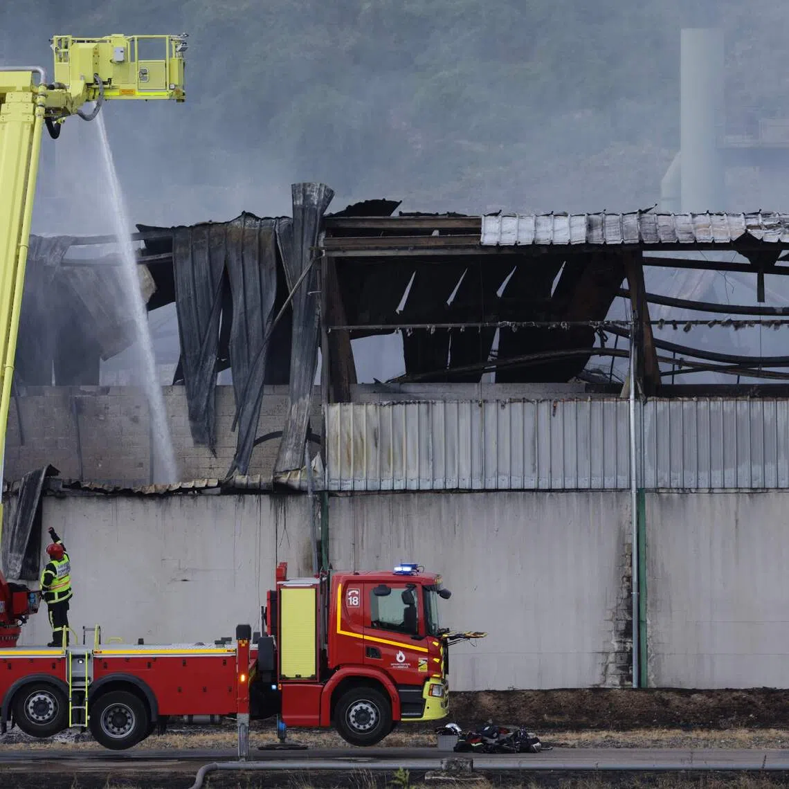 A French firefighter sprays water with a truck at an industrial warehouse in the north-eastern French village of Gandrange on Aug 2. The fire spewed foul smoke that gave residents headaches.
