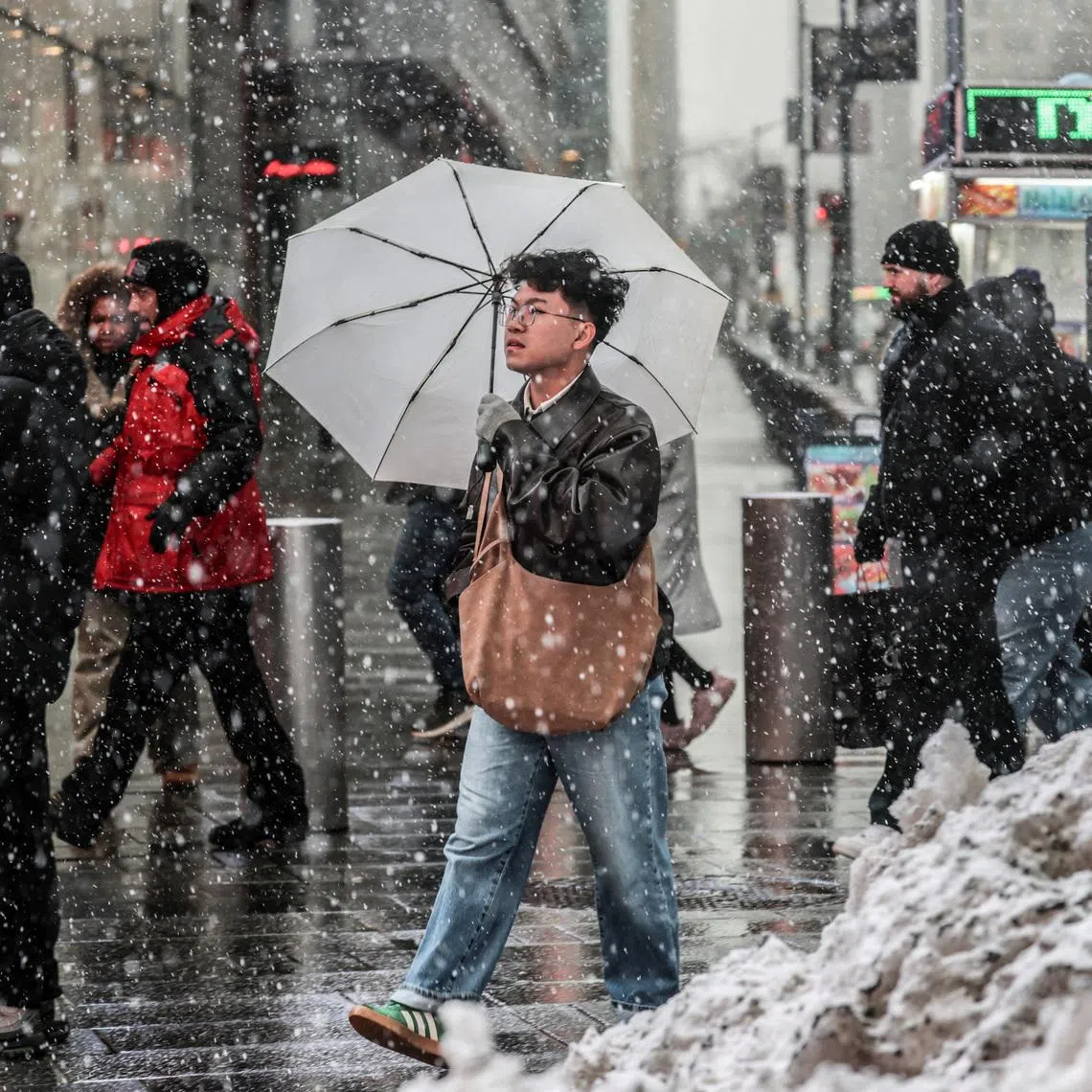 People walk on a street as snow falls during a winter storm in New York City, U.S., February 22, 2026.  REUTERS/Jeenah Moon