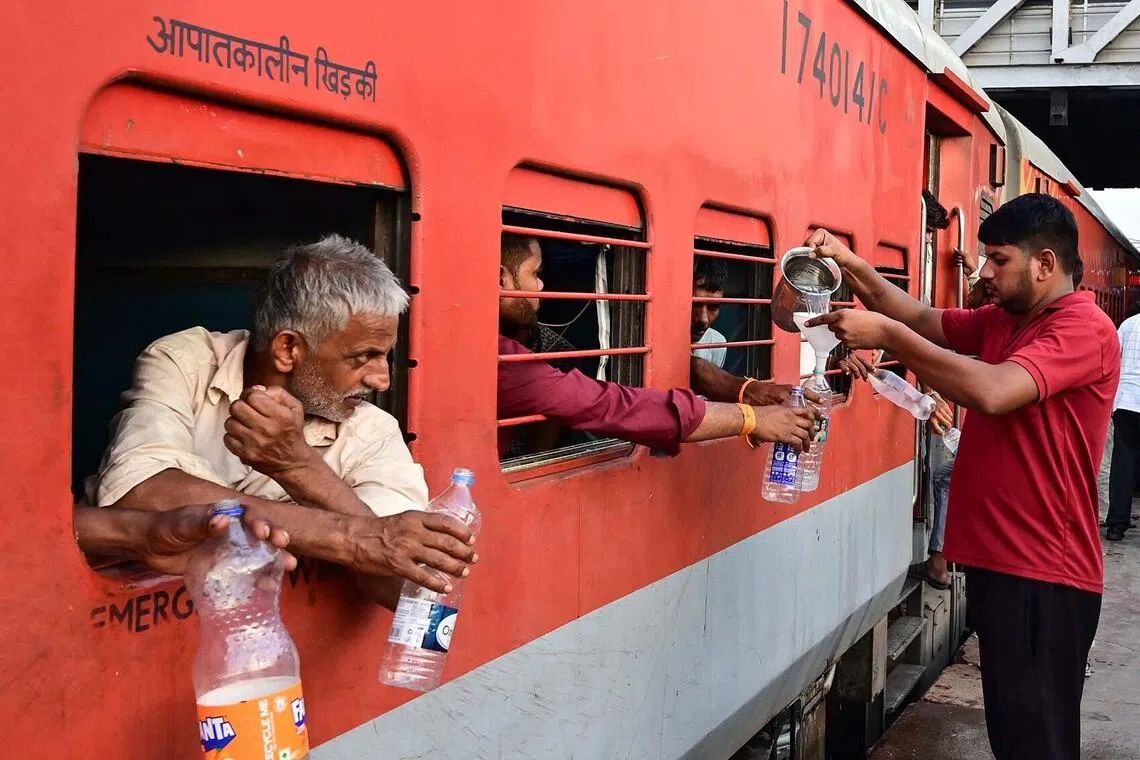 Vendor Parmod Khushwaha (right), a vendor, serving free drinking water to train passengers at the railway station in Ahmedabad. Every summer, local volunteers - including shopkeepers, porters, food vendors, and police personnel - pool their money to provide free drinking water to train passengers during the hot weather. 