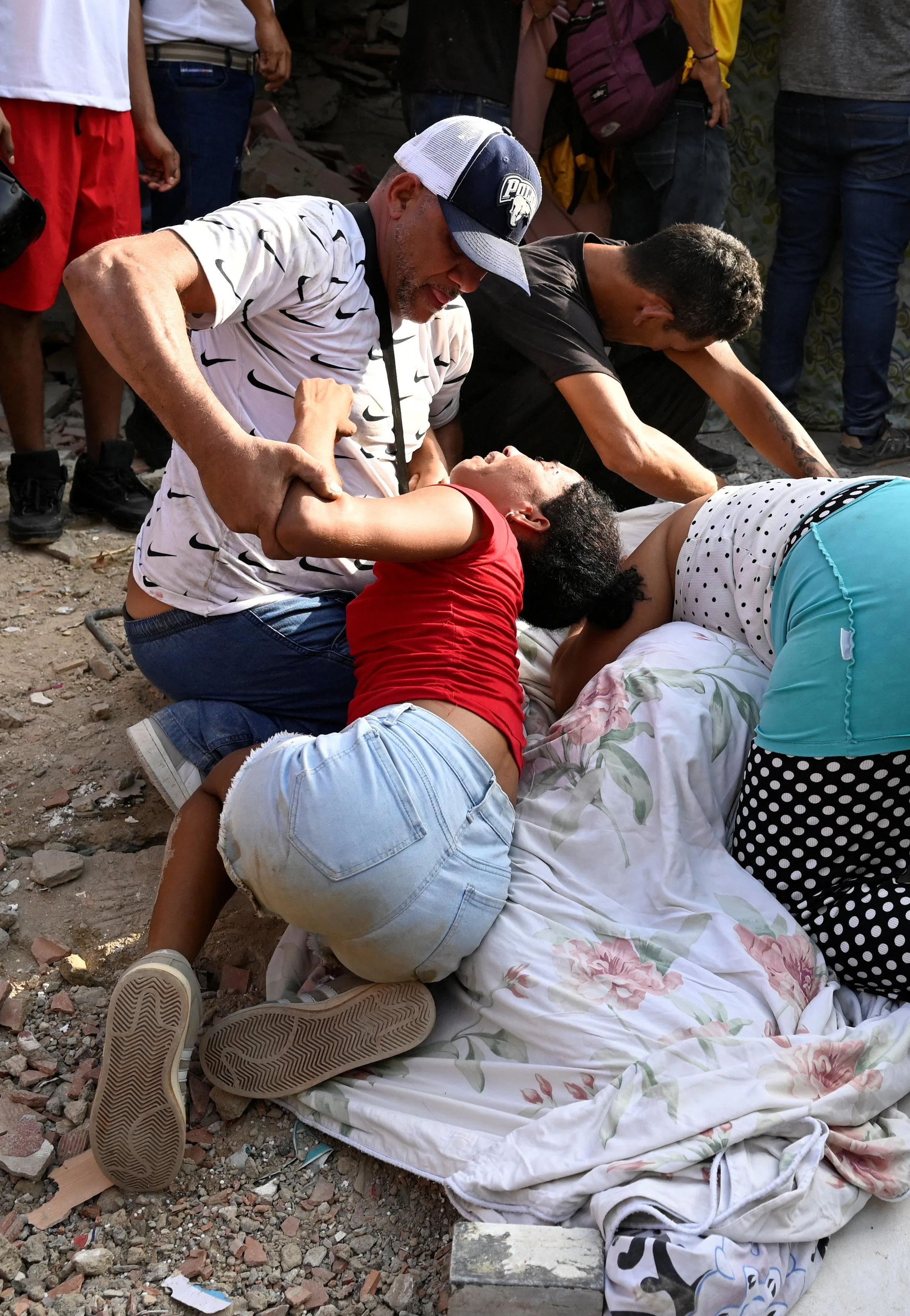 People mourn next to the body of a casualty, amid the rubble and debris of damaged buildings in the aftermath of earthquakes in La Guaira, Venezuela, June 25, 2026. REUTERS/Maxwell Briceno