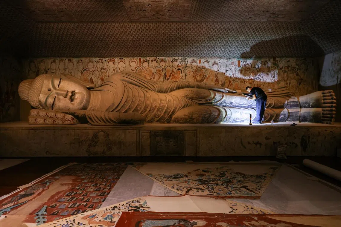 A contractor touching up a 13m-long Buddha sculpture ahead of the Sacred Caves: Dunhuang, Buddhism, And The Silk Road exhibition at the Asian Civilisations Museum.