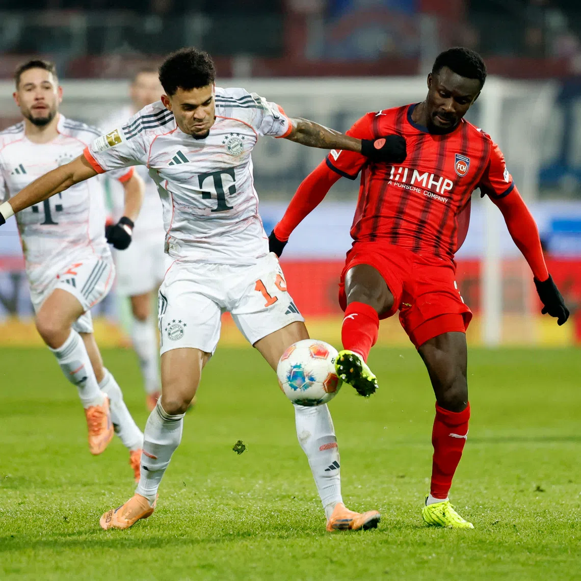Soccer Football - Bundesliga - 1. FC Heidenheim v Bayern Munich - Voith-Arena, Heidenheim, Germany - December 21, 2025 Bayern Munich's Luis Diaz in action with 1. FC Heidenheim's Sirlord Conteh REUTERS/Heiko Becker