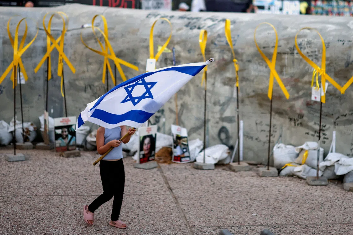 A girl carrying an Israeli flag through the "Hostages Square" in Tel Aviv, Israel, on Oct 14, 2025, following the release of hostages after a ceasefire between Israel and Hamas went into effect. 